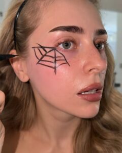 A wobbly spiderweb drawn freehand with black liquid liner next to the eye