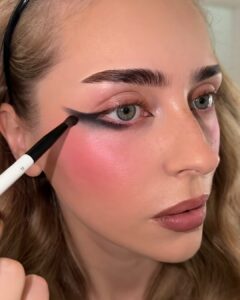 Smudging black eyeshadow out from the winged liner with a small fluffy brush