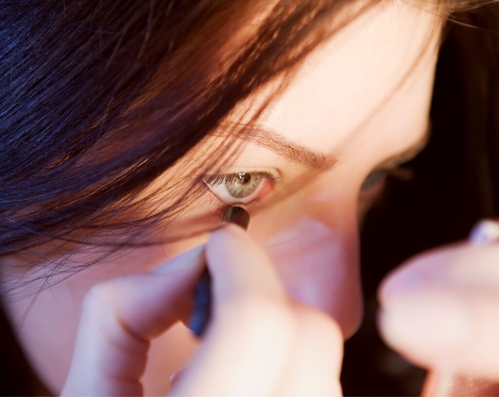 Placing a black eyeliner pencil at the outer corner of the eye to find the angle for a winged liner